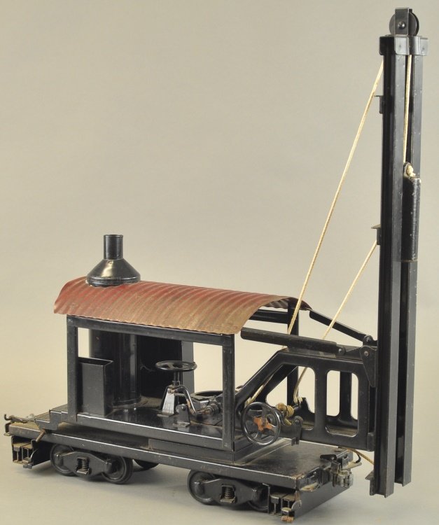 BUDDY 'L' LOCOMOTIVE PILE DRIVER: Pressed steel, very desirable example, black frame housing, red corrugated roof, vertical boiler, hand crank controls the one pound cast iron weight, able to pound the ground, stabilizer beams on flat