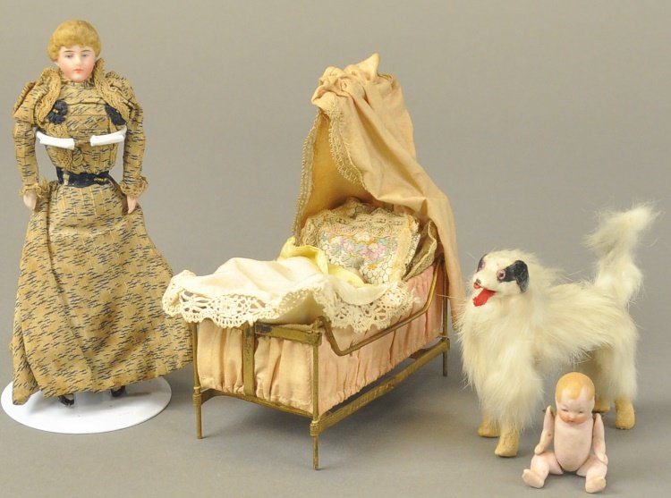 DOLL BED WITH BABY, MOTHER AND DOG: Mother dressed in long Victorian original print dress with hooded cradle in pink fabric with bedding, jointed bisque baby doll and small bisque baby in cradle, along with fur dog. Bed 6" h. x 5" l. Do