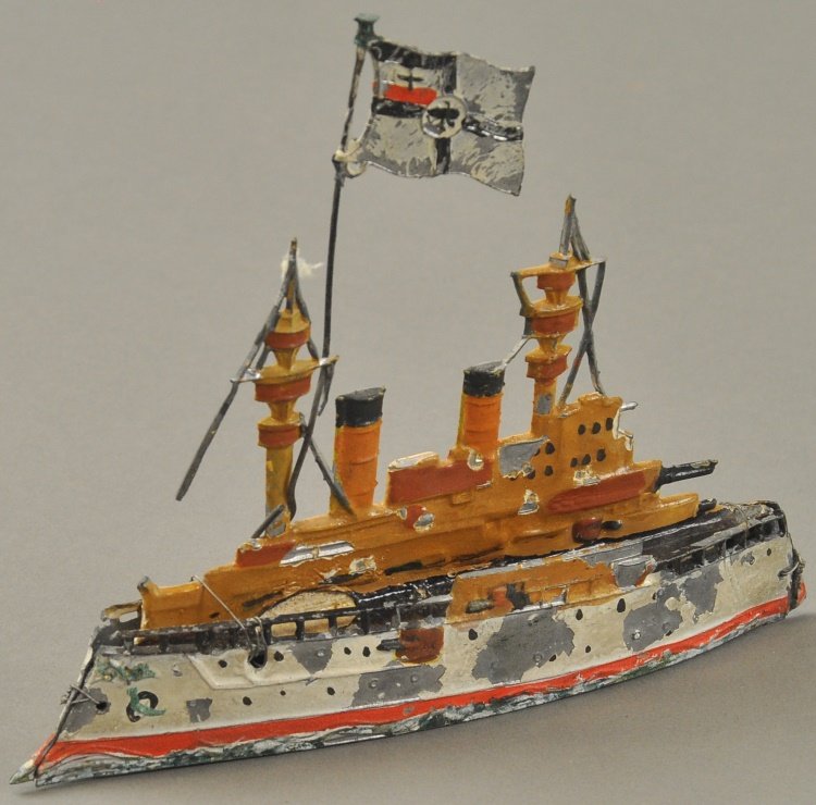 EARLY IMPERIAL GERMAN WARSHIP: Heavily cast lead example is hand painted, features embossed lead upper deck casting, large German flag, railed deck, hull held together with wiring as repair. 6 1/8" l.