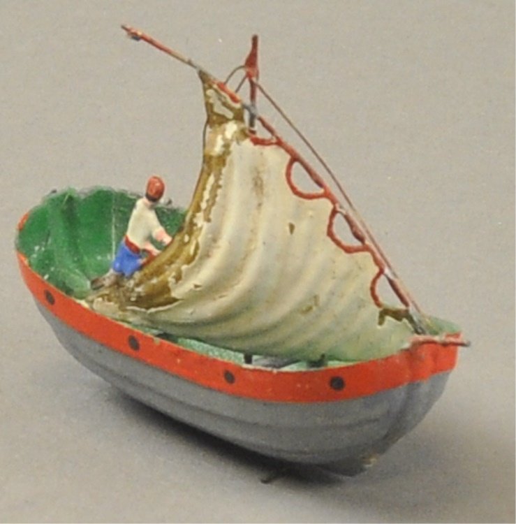 BUCHNER SAILBOAT: Germany, hand painted tin example, features delicate rigging and full sail, sailor depicted on board with steering pole. 2 3/4" l .