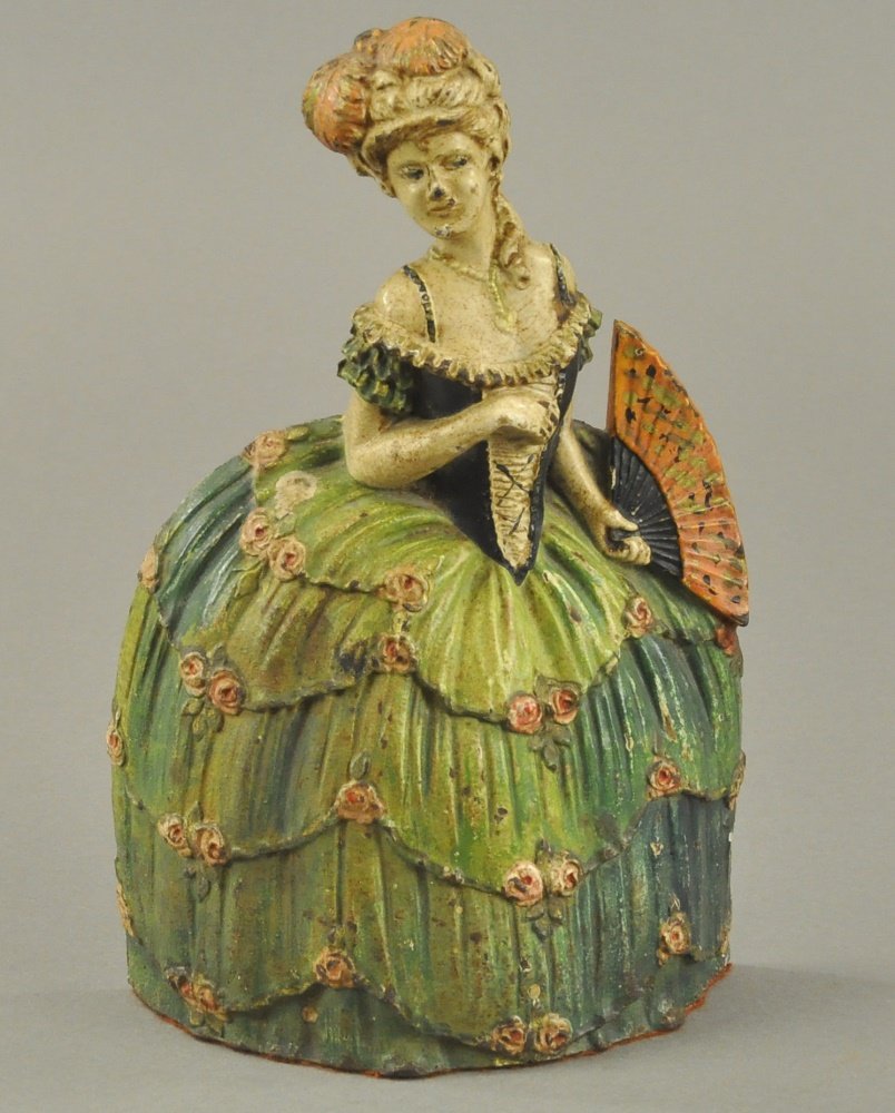 WOMAN IN HOOP SKIRT DOORSTOP: Waverly Studios, marked "Trademark WS Pat Applied For," depicts Parisian type woman in elaborate green hoop skirt with fan in hand, pink highlights throughout. 9 3/8" h.