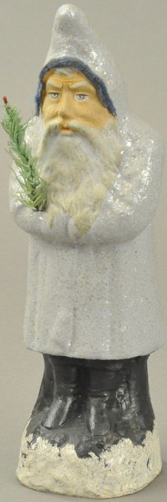 BLUE-GREY COMPOSITION BELSNICKLE: Germany, a most unusual color robe, composition Belsnickle with blue trim around hood, holding feather tree sprig in folded arms. 10" h.