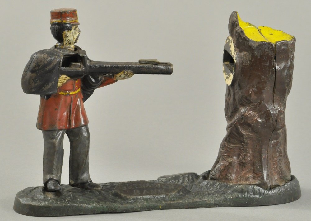 GRENADIER MECHANICAL BANK: Mfg. John Harper & Co., England, circa 1890, cast iron and hand painted, debossed lettering on base, cock rifle, place coin and press down on figure’s foot to shoot coin into tree. Ex. Griffith Coll