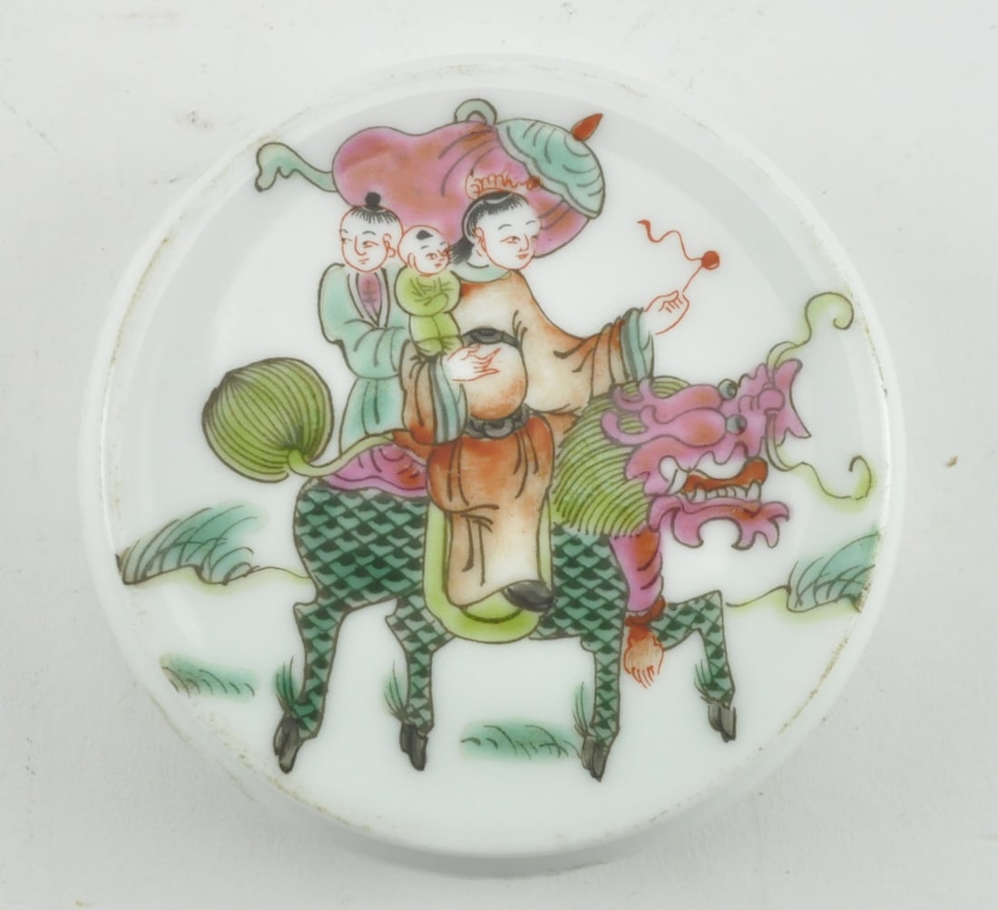 QING DYNASTY FAMILLE ROSE "QILIN" PAPERWEIGHT 清 粉彩麒麟送é: A Qing dynasty famille rose paperweight. The circular shaped paperweight depicting a man carrying a young child with his attendant holding a canopy umbrella, riding on a qilin, symbolize bringing an e