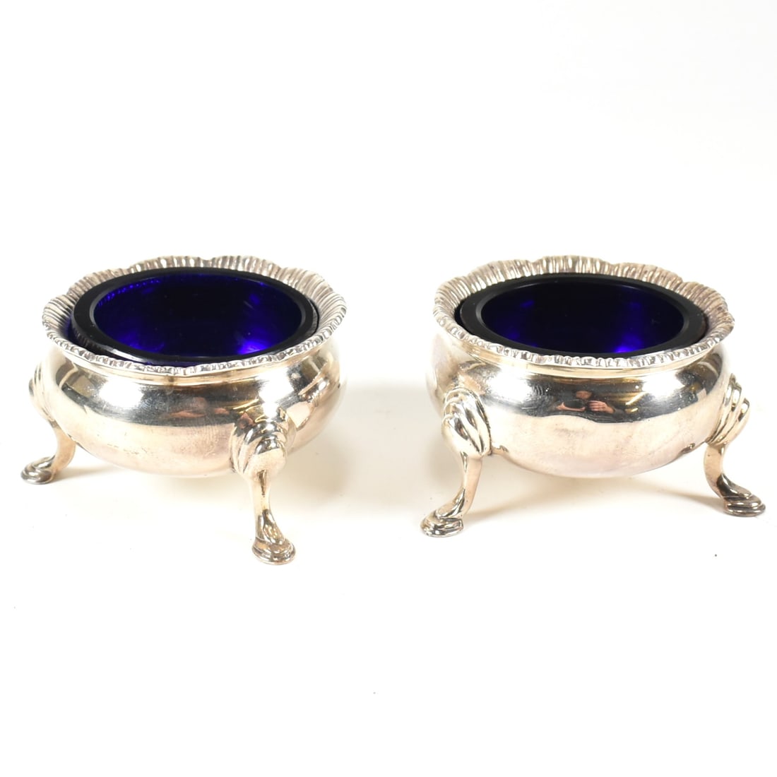 PAIR OF SILVER HALLMARKED BLUE GLASS LINED TABLE SALTS: A pair of silver hallmarked blue glass lined table salts. Hallmarked London, makers mark illegible. Date letter O for 1929. Weight exc. liners approx 95g.