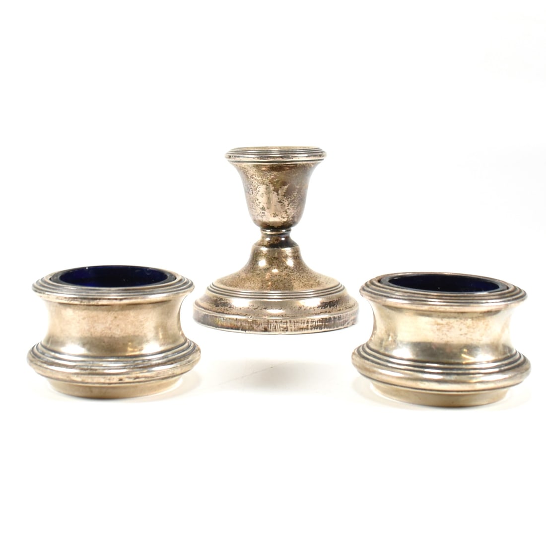 GEORGE V HALLMARKED SILVER SALTS & STUB CANDLESTICK: A pair of George V hallmarked silver table salts. The salts, each with blue glass liners. Hallmarked Birmingham 1945, sponsors mark illegible. Weight exc liners 27. Together with a silver stub candles