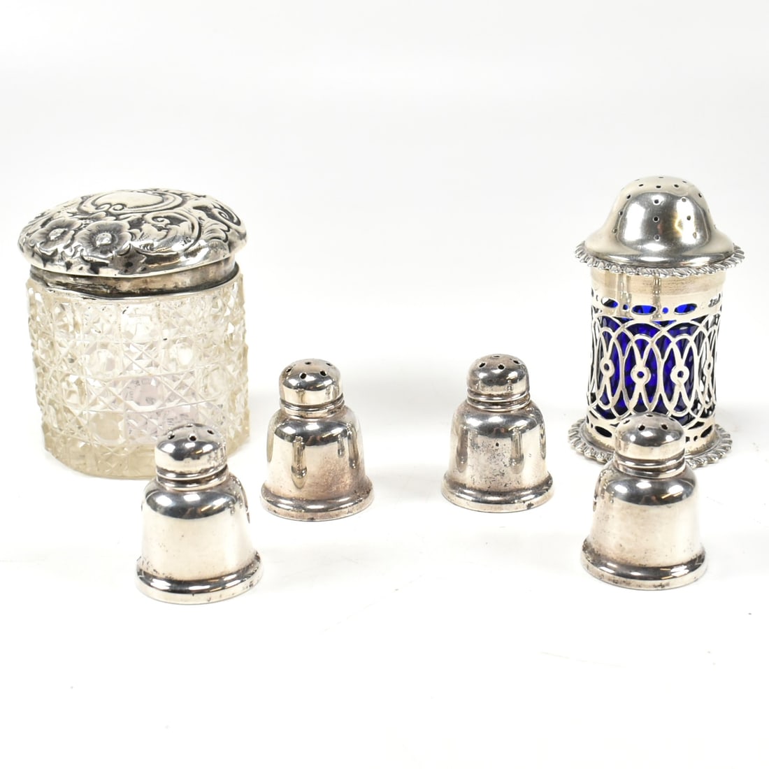 HALLMARKED SILVER PEPPERETTE T/W SET 4 STERLING SILVER PEPPERETTES & A POT: A set of 4 sterling silver pepperettes. Stamped Sterling with makers mark to the base. Together with a hallmarked silver pepperette having blue glass liner. Hallmarked London, sponsors mark JCL. Also