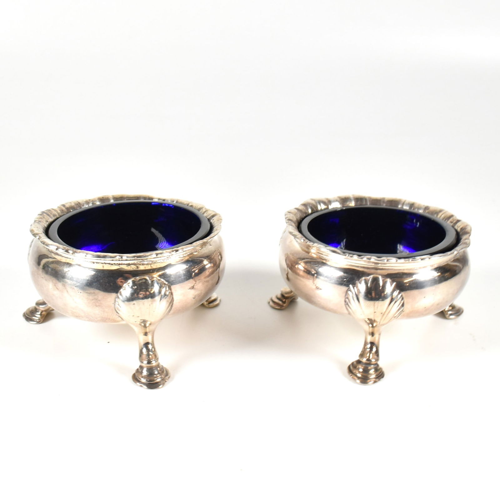 PAIR SILVER HALLMARKED GEORGE III BLUE GLASS LINED TABLE SALTS: Matched pair of silver hallmarked blue glass lined table salts. Both George III examples, matching patterns, silversmiths marks differing and partially legible. Weight excluding liners 155g.