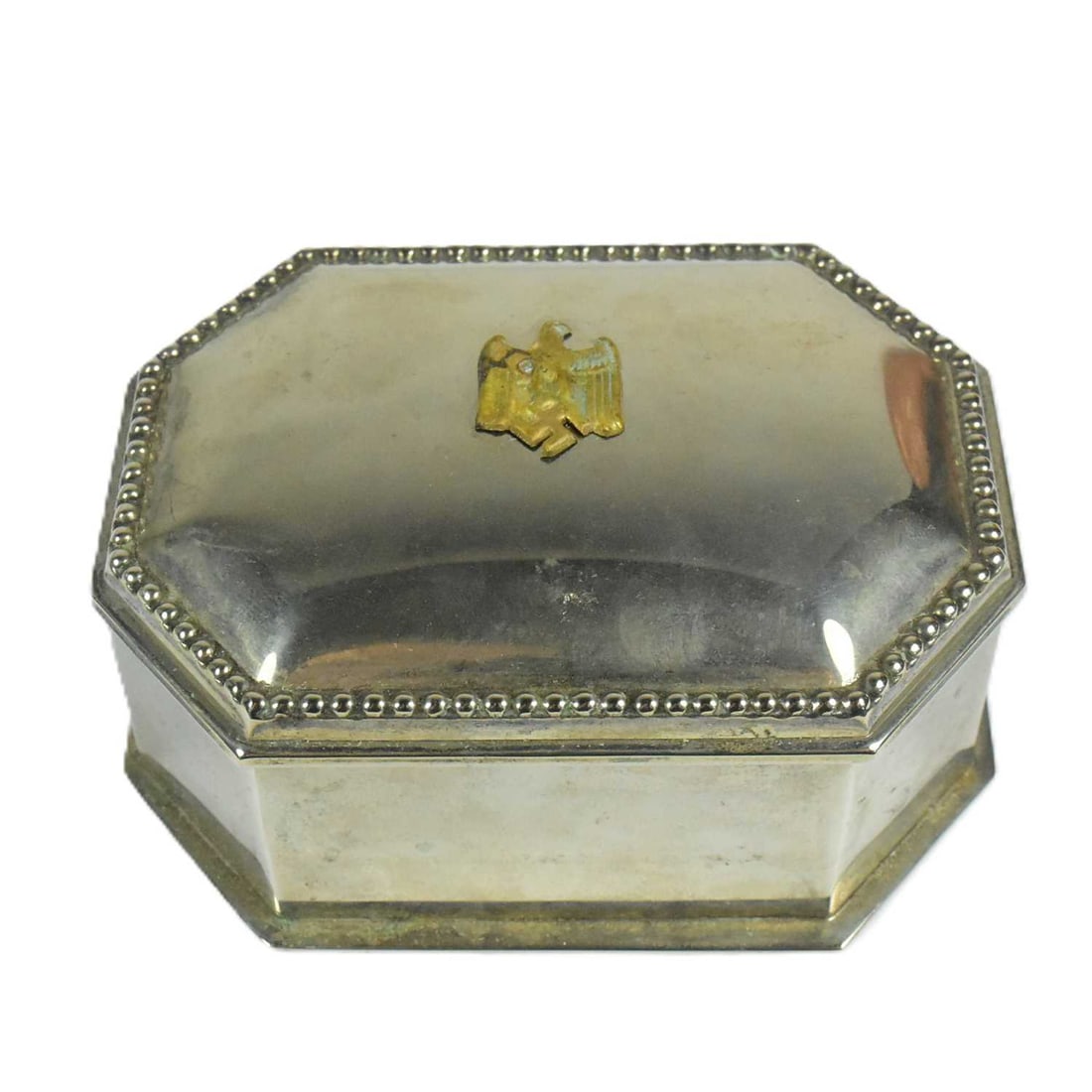 WWII SECOND WORLD WAR STYLE GERMAN TRINKET BOX: A WWII Second World War Third Reich Nazi German style silver plated trinket box with applied brass eagle swastika badge and a red velvet lining. Measures approx 4x10x8cm. Due to the nature of some ite