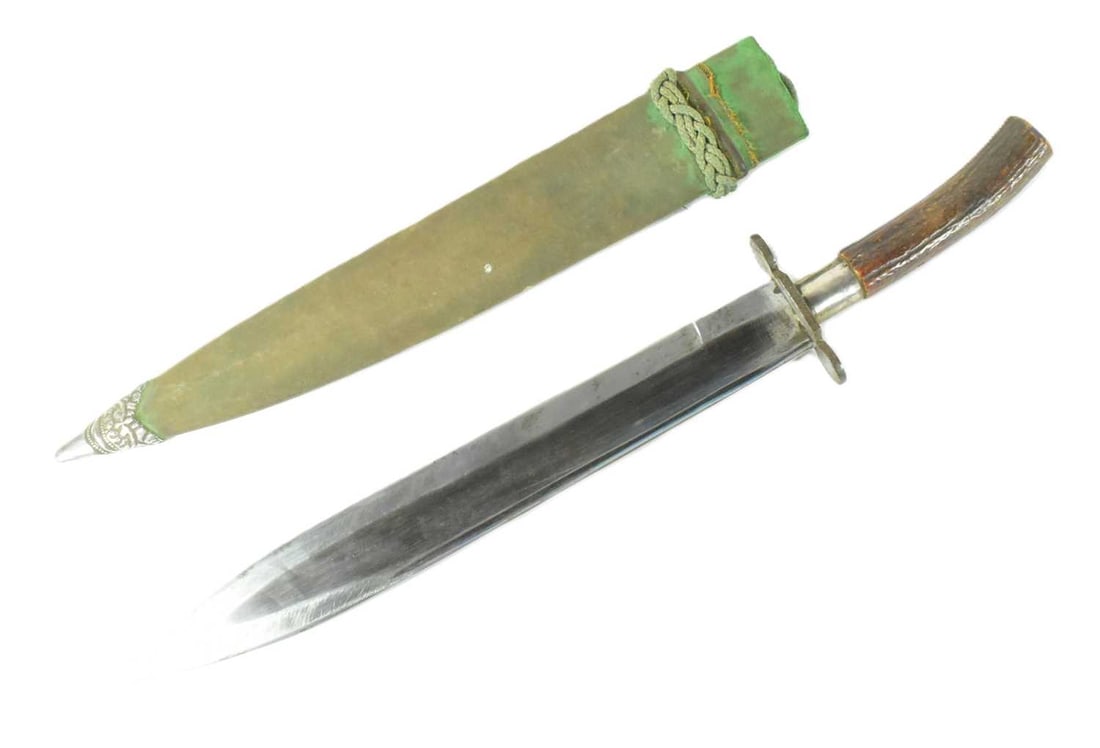 20TH CENTURY INDIAN BOWIE KNIFE: A 20th Century Indian Bowie knife machete having a stag horn grip, knuckle guard and a deep fullered blade housed in a silver-tipped velvet wrapped wooden scabbard. Measures approx 43cm.