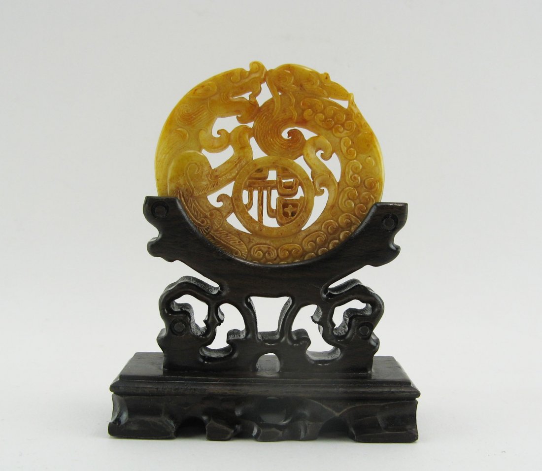 Amulet: Yellow jade, open worked decoration of a dragon. On a wooden base. Diameter of 7 cm. Comes with another amulet.Â