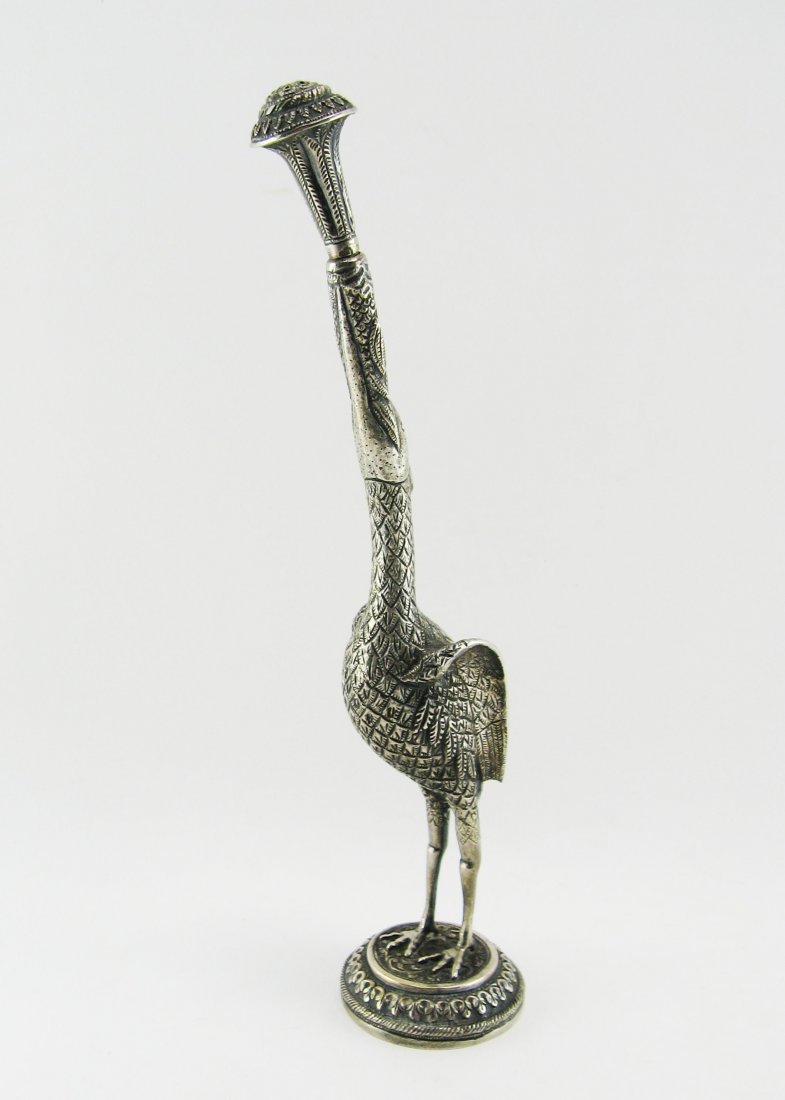 Sprinkler: Silver, standing Ibis on a round base. In its beak it's holding a turnable sprinkler. Batavia, start of the 20th century. Height 31 cm.Â