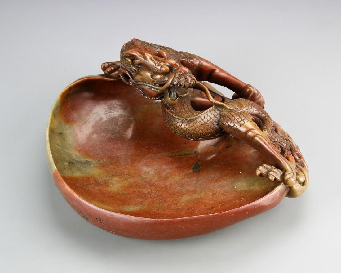 Chinese Shoushan Stone Brush Washer: China, 19th C., Shoushan stone brush washer, with a deeply carved dragon motif, in a deep red-brown mottled hue. Width 9 1/4 in., Length 7 1/2 in.