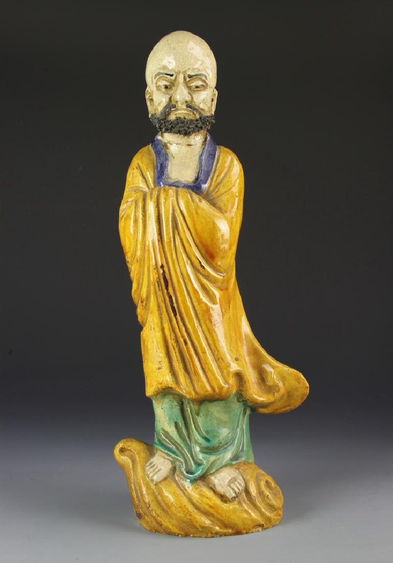 Chinese Yellow Glazed Darama: China, Ming Period, yellow glazed Darama, standing on a stylized wave, with flowing yellow robes and a regal beard, repair on neck. Height 18 in.