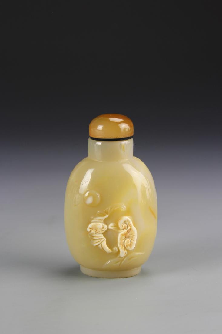 Chinese Agate Snuff Bottle: China, ROC Period, agate snuff bottle, in a pale yellow brown color, with a raised bat and plant life design on the front. Height 2 3/4 in.