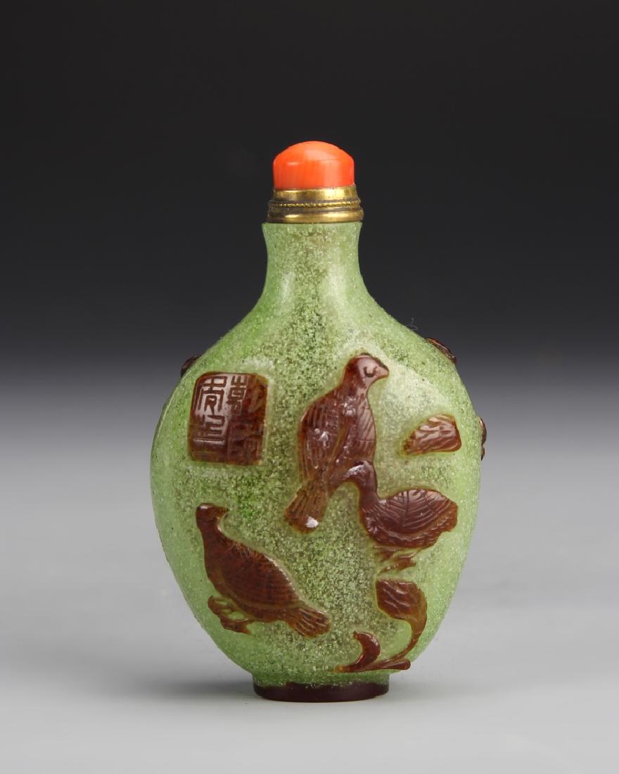 Chinese Peking Glass Snuff Bottle: China, Peking glass snuff bottle, in flattened ovoid form, speckled green shade glass with craved brown birds, with a coral stopper. Height 2 3/4 In.