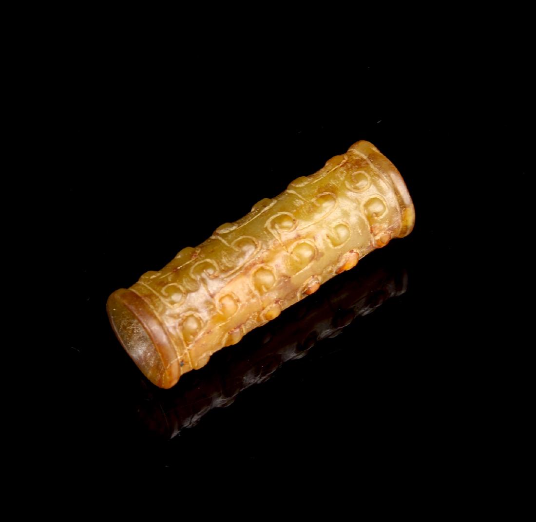 Chinese Jade Lezi: China, Jade Lezi, well-carved circular patterned and raised motifs on all sides with two rimmed borders, cylindrical in form with subtle patina. Length 2 in.