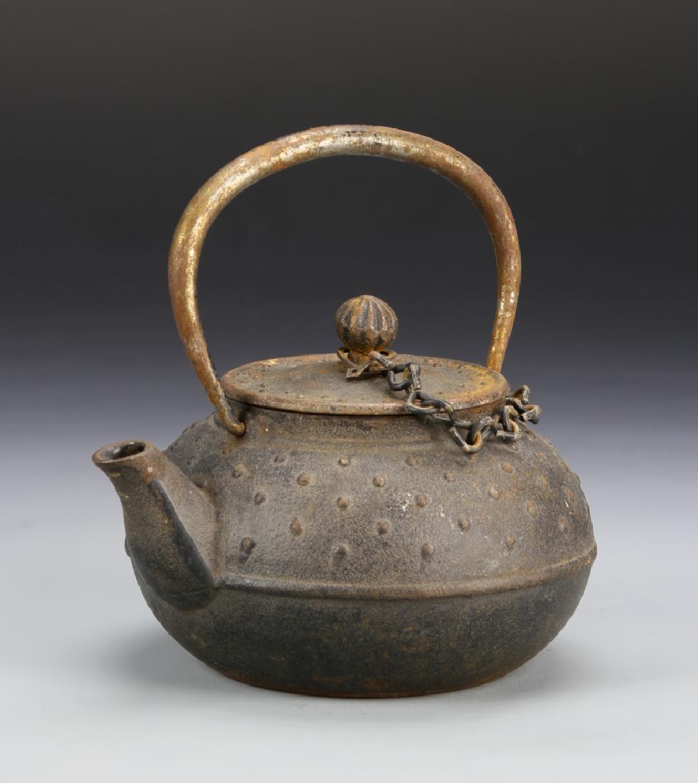 Japanese Metal Teapot: Japan, 19th C., metal teapot, with large handle, chain detail, textured surface, and with a cover. Height 5 1/2 in., Width 6 in.17550