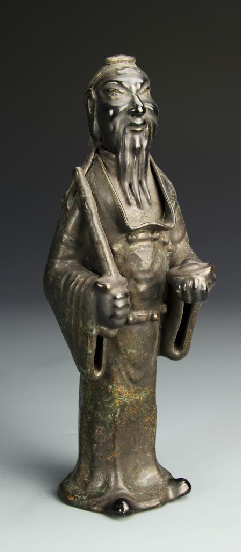 Chinese Bronze-Like Porcelain Figure: China, bronze-like porcelain standing figure of wise, bearded man in robes, holding a scepter in his left hand and half a peach in the other. Height 9 3/4 in.
