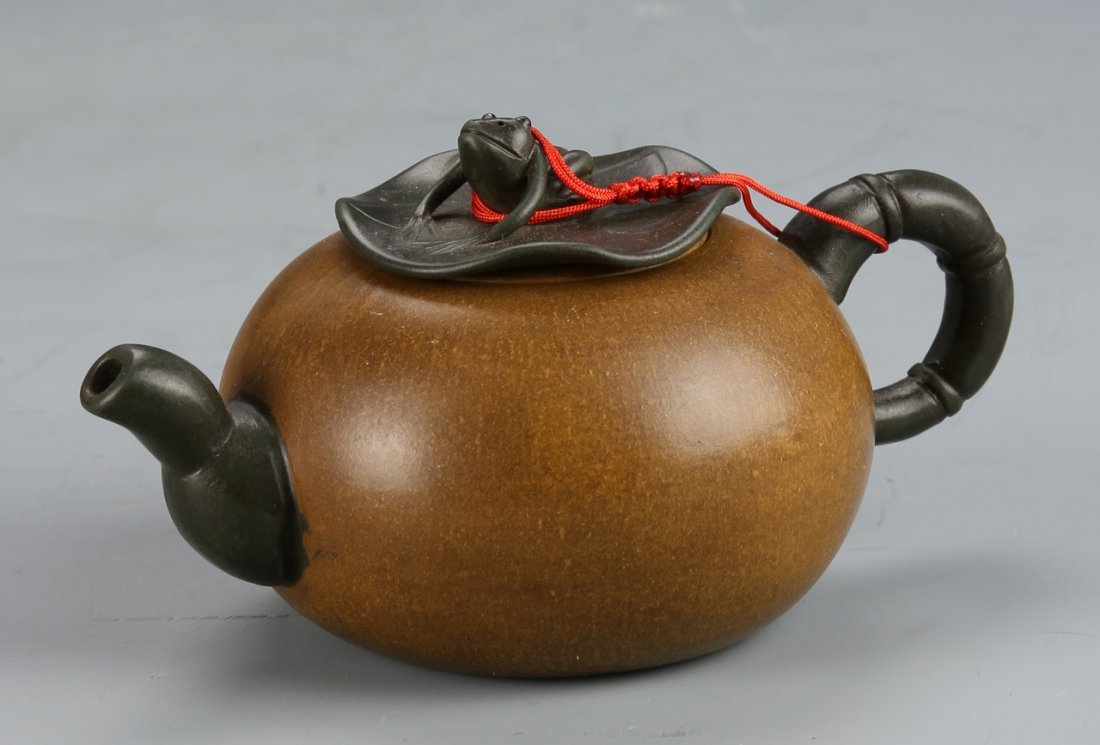 Chinese Yixing Teapot, Signed Zhou Gui Zheng: China, Yixing teapot, in a bulbous form, with a frog figure decorating the top; the handle, spout, and lid are painted black, signed Zhou Gui Zheng. Height: 2 3/4 in., Width: 5 1/2 in.