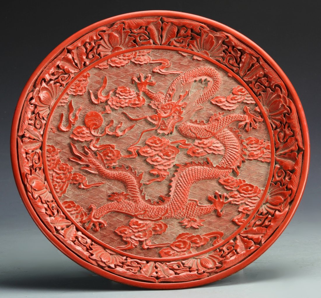 Chinese Cinnabar Plate: China, 19th C., cinnabar plate with carved central decoration of five-clawed dragon chasing a pearl through clouds, encircled with floral border, mark on base. Diameter 11 1/2 in.