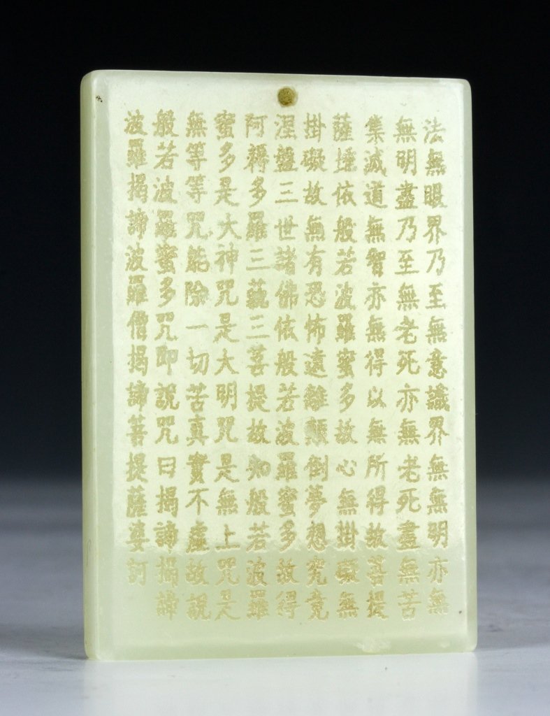 Chinese Carved Jade Buddhist Scripts: China, carved Buddhist scripts in Chinese calligraphy on a square of white jade, featuring a small relief carving of a standing Buddha. Height 2 1/4 in., Length 1 5/8 in.
