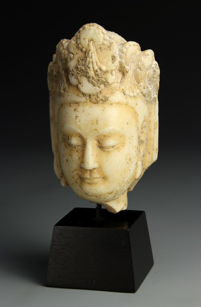 Chinese Carved Limestone Head: China, carved limestone head of Guanyin with an elaborate headdress, and a serene facial expression, on a display pedestal. Height without base 5 1/2 in., Width 3 in.