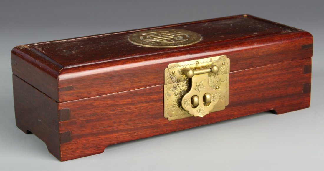 Chinese Hardwood Jewelry Box: China, hardwood jewelry box, carved smoothly with rounded edges, decorated with metal hinge incised with floral pattern and auspicious symbol on lid. Length 10 in., Width 4 in., Height 3 in.