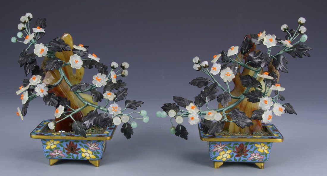 Two Chinese Jade Flowers with Cloisonne Planters: China, two jade flower pots with white and yellow flowers and detailed leaves, and cloisonne planters with blue backgrounds and colorful flower details with footed bases. Height 6 in.