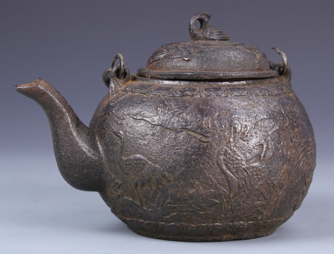 Chinese Iron Teapot: China, 19th C., iron teapot with handle, with bird and plant life motifs, and bird figure handle on top. Height 8 in., Width 8 1/2 in.