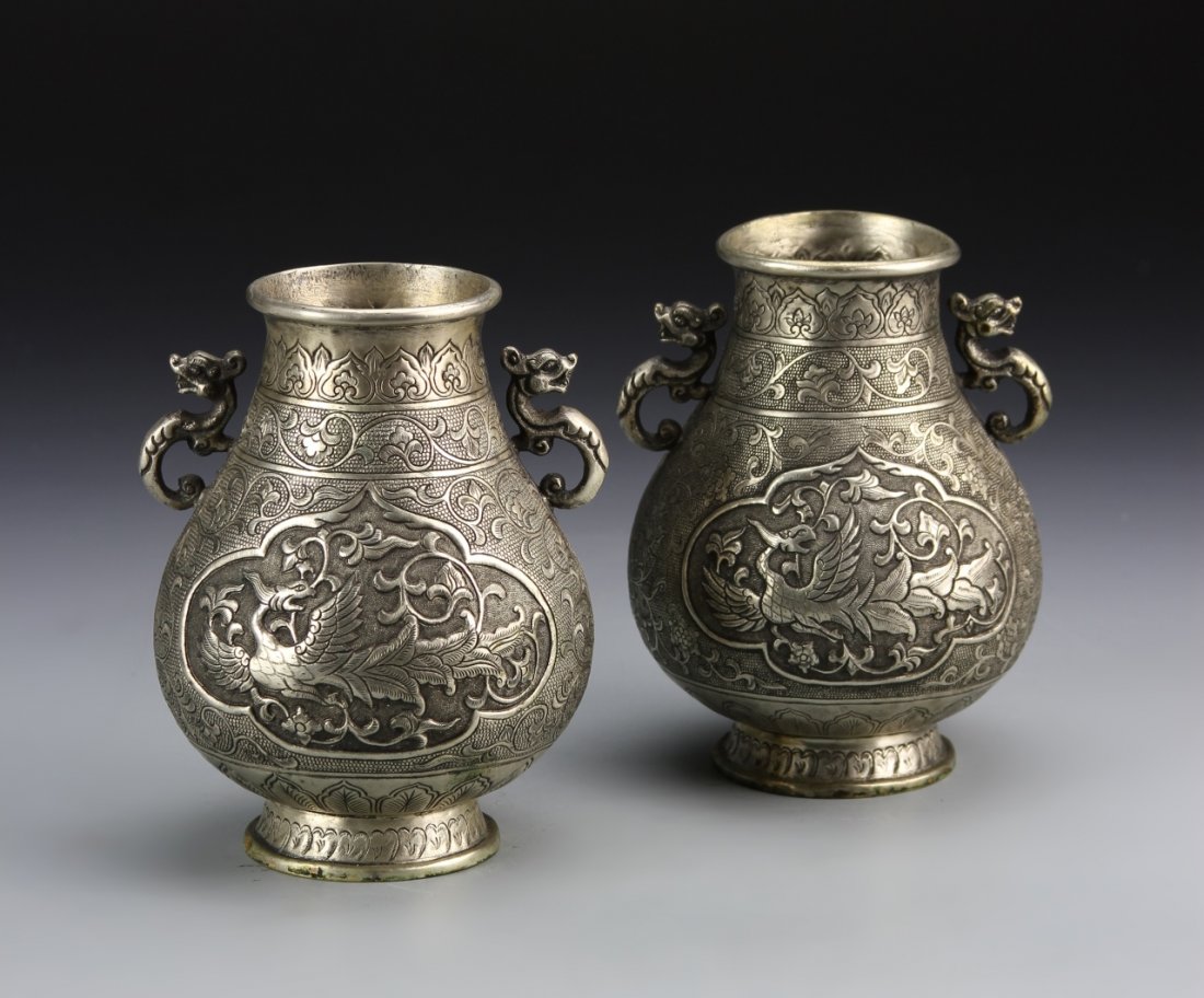 Pair of Chinese Silver Vases: China, 19th C., a pair of silver vases, intricate metalwork patterns and detail bordering central images of mythical birds, handles in the shape of simplified dragons, mark on base. Height 4 7/8 in.