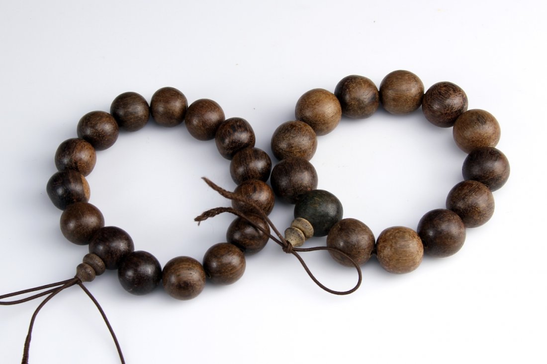 Two Chinese Wooden Bracelets: China, two wooden bracelets, each with 15 beads, all beads in spherical form, in dark brown hues, with natural wood grain showing. Diameter 3 3/4 in.