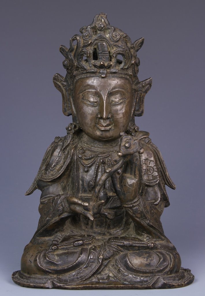 Chinese Bronze Buddha: China, Ming Period, bronze Buddha, in seated position holding scepter, with stylized facial features, incised natural motif on back of robe, decorated with jewelry and crown. Height 8 in.