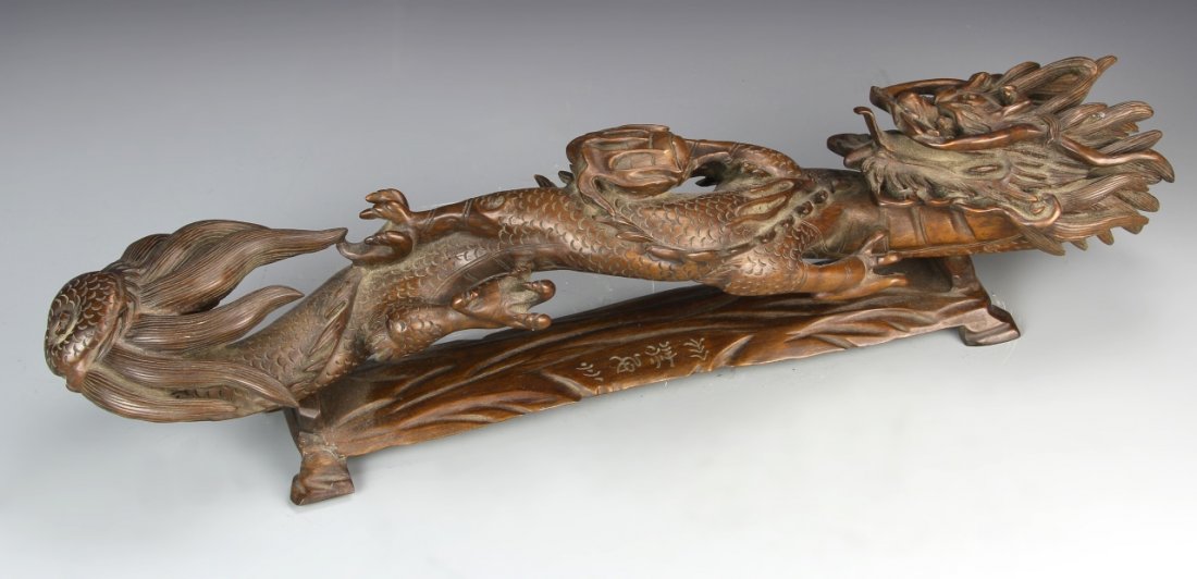Chinese Boxwood Ruyi Scepter: China, 19th C., boxwood ruyi scepter, in the form of a dragon, with deeply carved linear details, and carved wood base with Chinese characters. Length 22 in.