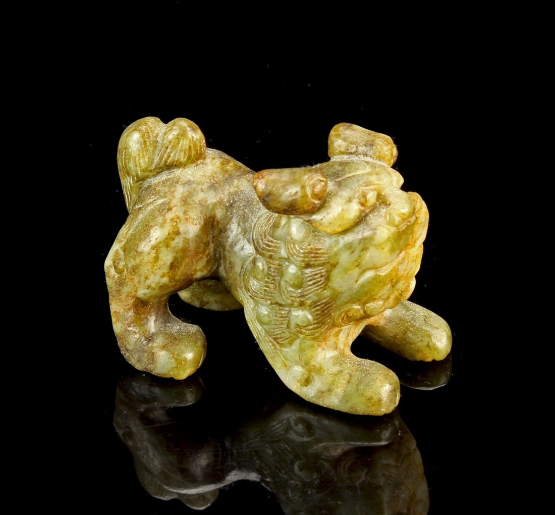 Chinese Jade Dog: China, jade dog, standing upright on all fours in a playful gesture, curly hair and tail are shown in relief, the surface of the stone carved in a way to show the natural texture. Length 2 1/2 in.