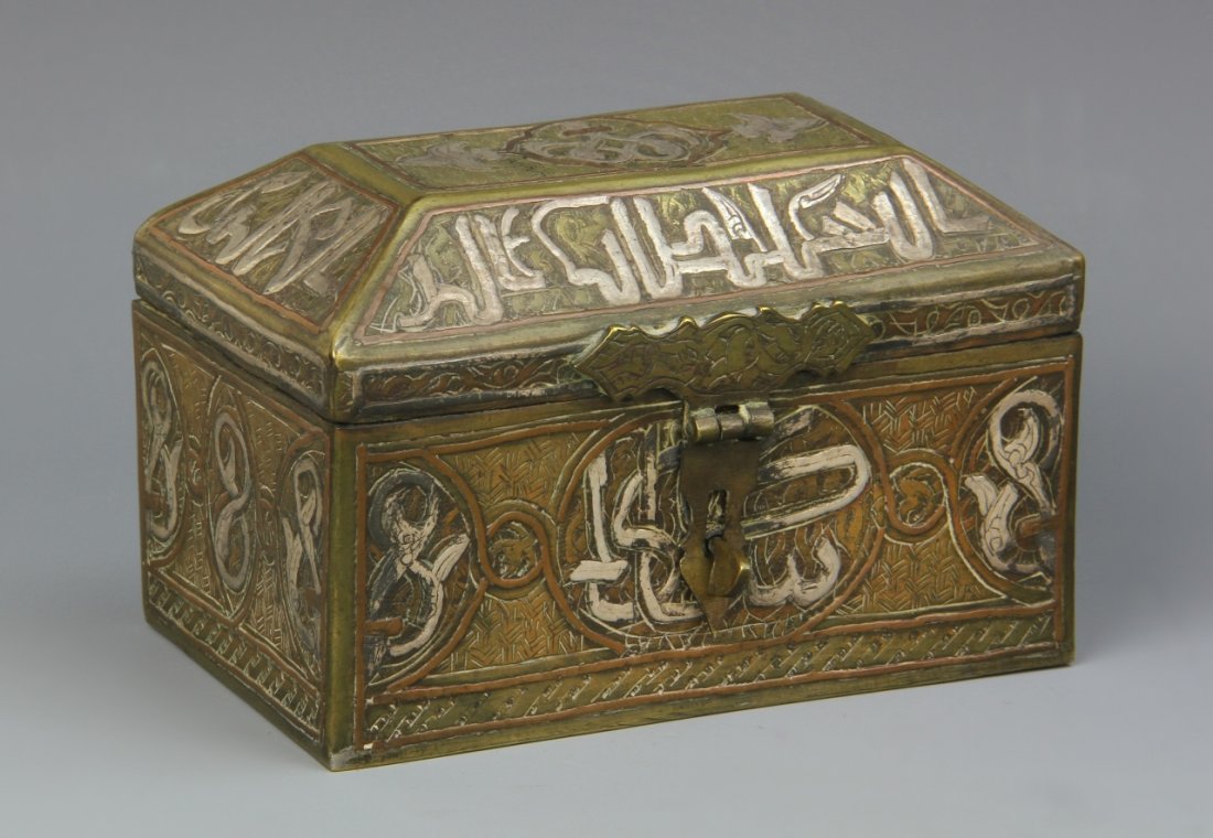 Arabian Metal Box with Silver Inlays: Arab, metal box with silver inlays, with a geometric lid, carved linear designs, metal details, and Arabic characters. Length 4 in., Height 2 3/8 in., Width 2 1/2 in.