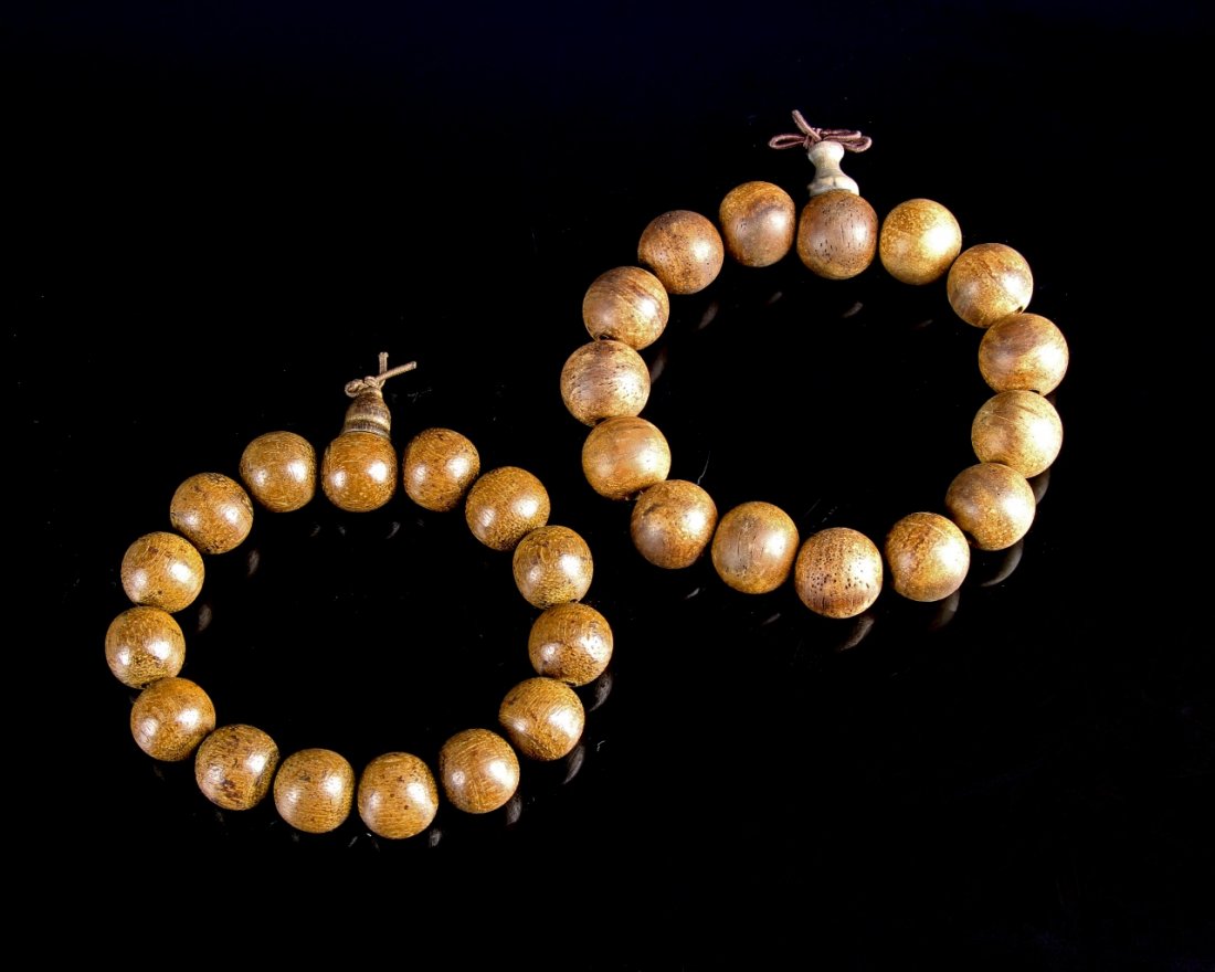 Two Chinese Chen Xiang Wood Bracelets: China, two Chen Xiang wood bracelets, each with fifteen beads, light natural wood grain color, on elaborately knotted brown cord, one Qinan Chen Xiang, one Tai. Diameter 3 in.