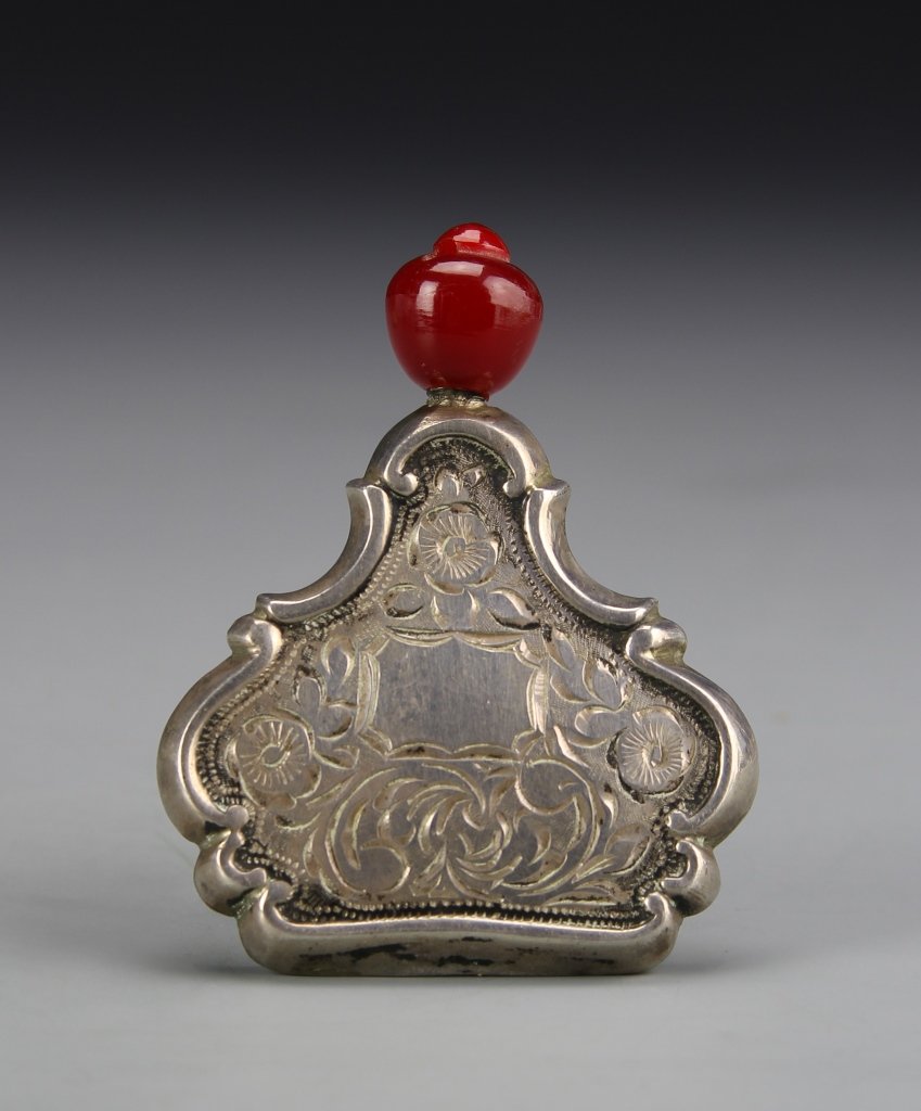 Chinese Silver Snuff Bottle: China, 19th C., very rare silver snuff bottle, with bright red agate stopper, deeply carved floral motifs across the surface, and patina. Height 2 5/8 in.