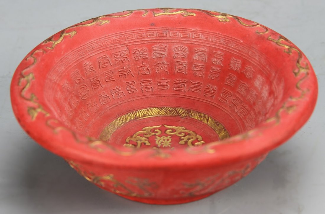 Chinese Red Clay Bowl: China, red clay bowl, flared rim on footed base, decorated throughout with calligraphy characters in relief, key-fret pattern, and gold dragons accenting the rim, Qianlong mark on base. Height 1 3/4 i