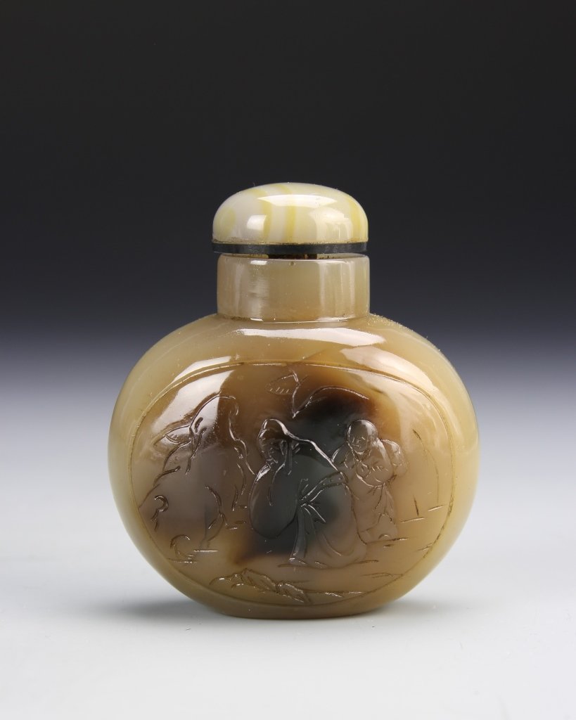 Chinese Agate Snuff Bottle: China, 19th C., agate snuff bottle, flattened circular, carved design on front of body, mottled hue, with striations in the stone. Height 2 1/2 in.