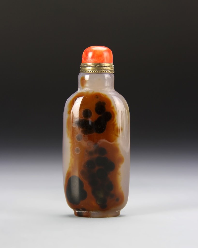 Chinese Agate Snuff Bottle: China, 19th C., agate snuff bottle, flattened rectangular form, with slightly raised base, white hue, with dark design on front, coral stopper. Height 3 1/4 in.
