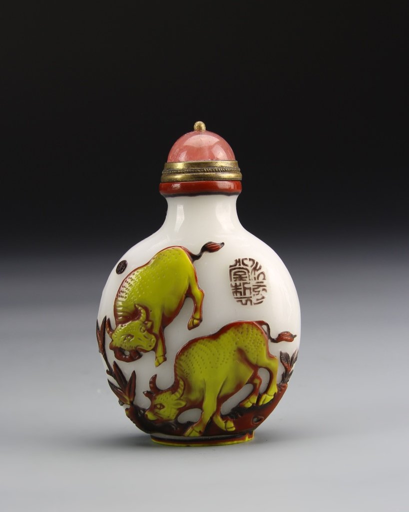 Chinese Carved Peking Glass Snuff Bottle: China, 19th C., carved Peking glass snuff bottle, white ground, with carved design of grazing bulls, painted in a bright yellow, coral colored topper. Height 2 7/8 in.