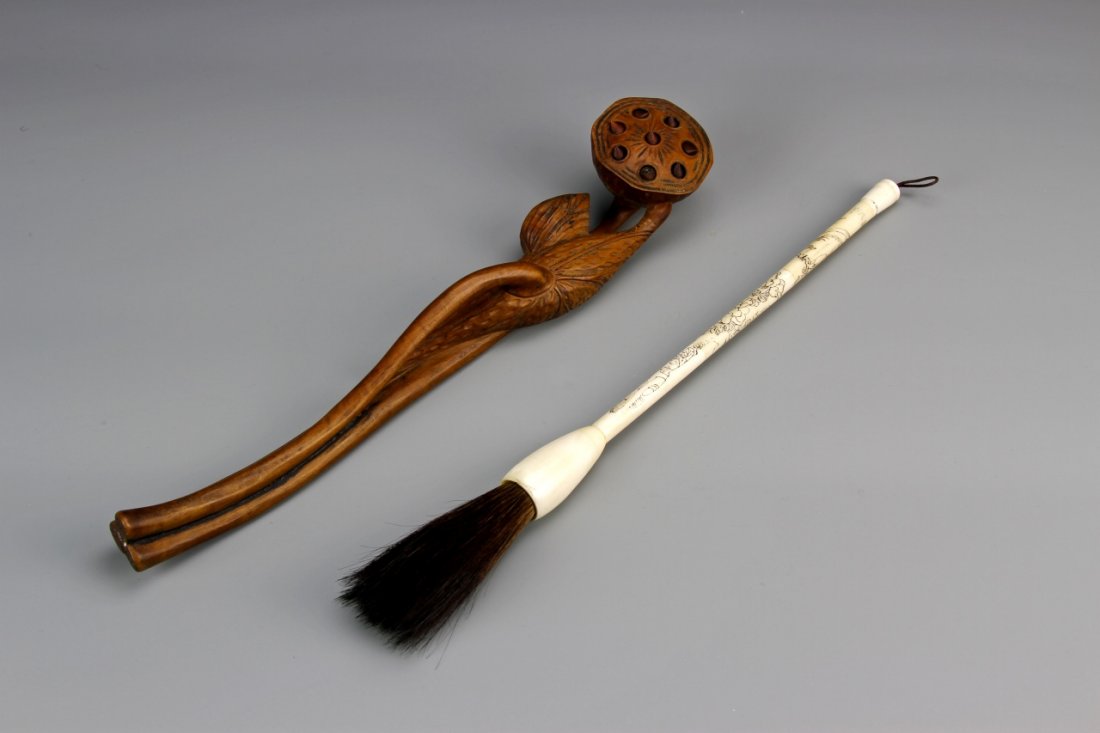 Chinese Ruyi Scepter and a Bone Brush: China, wooden Ruyi scepter, with carved floral motifs, and natural wood grain, and a bone brush, with detailed linear accents across the handle. Height 11 in.