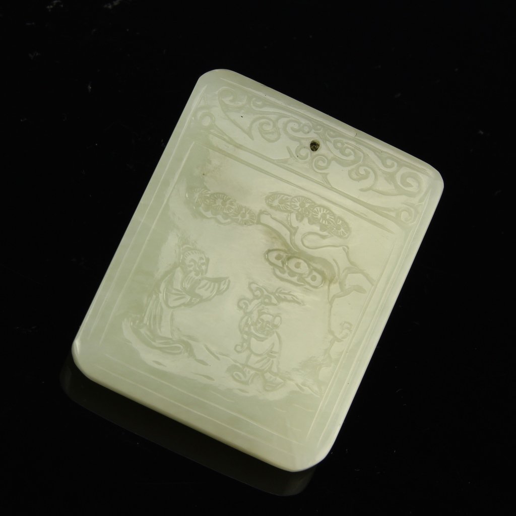 Chinese Hetian Jade Pendant: China, Hetian jade pendant, rectangular light pendant with image of two figures under a tree, pattern decoration at top, incised calligraphy on back. Height 2 in.
