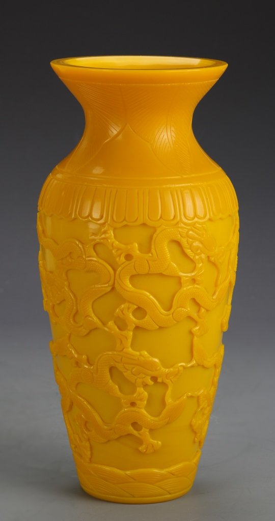 Chinese Peking Glass Vase: China, Peking glass vase, in vivid yellow, with a flared rim, embellished with four-clawed serpentine dragons and stylized waves at the foot. Height 10 in.