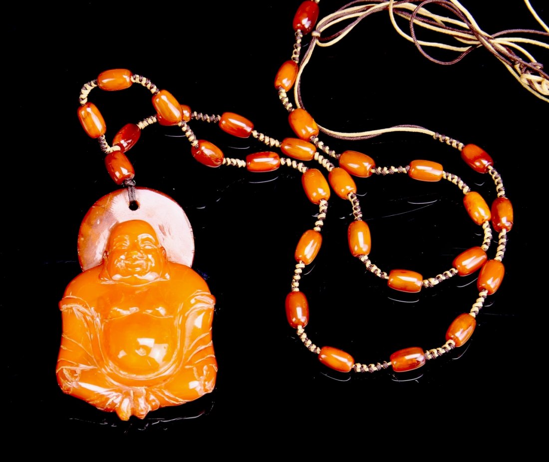 Chinese Carved Mi-La Buddha Pendant: China, Qing Period, carved Mi-La Buddha pendant, figure in seated position, smooth shine surface, orange in color, with matching Mi-La beads necklace. Length 2 in.