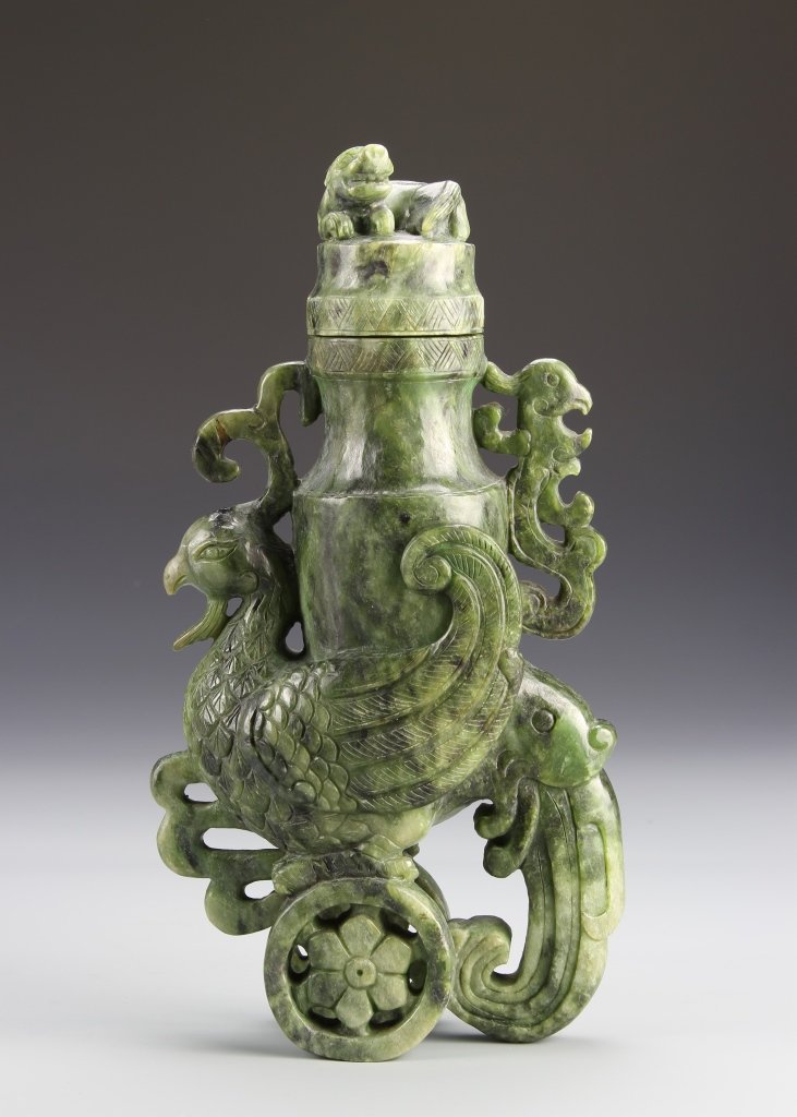 Chinese Jade Vase: China, jade vase, seated in an attached cart in the form of a rooster, mythical figure seated atop vase, molded green hue, striations in the stone. Height 11 in.