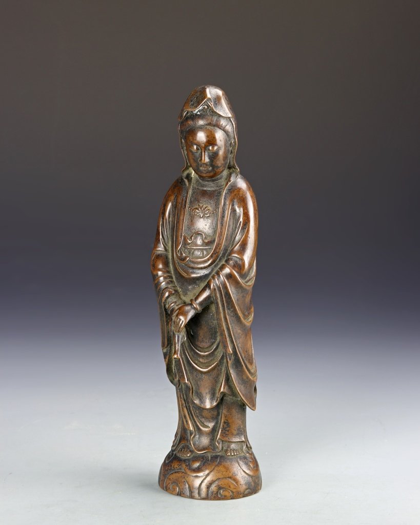 Chinese Bronze Guanyin Figure: China, 19th C., bronze Guanyin figure, detailed statue depicting the Guanyin figure dressed in flowing robes, hands folded in front of body and eyes lowered in a calm expression, standing a top a smal