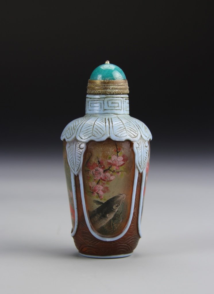 Chinese Peking Glass Snuff Bottle: China, Peking glass snuff bottle, blue stopper, raised relief of petal lappets in pale blue draped from the shoulders, with underlying fish and plant motif. Height 2 7/8 in.