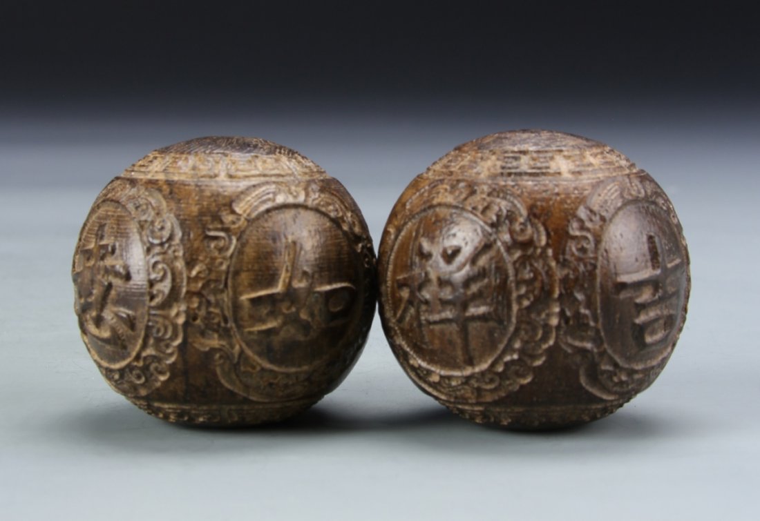 Two Chinese Cheng Xian Wood Balls: China, two Cheng Xian wood balls, carved in raised relief, with auspicious symbols, decorative details, and natural wood grain showing. Diameter 1 1/2 in.